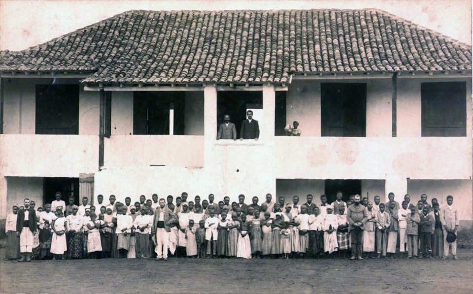 grupo de indigenas e portugueses junto a casa.jpg